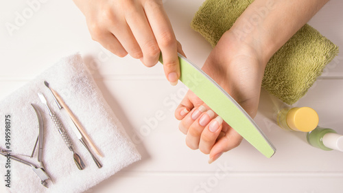 Manicure. A woman files her nails. Shorten long nails. Manicure tools. Home nail care, SPA, beauty. Long natural nails. Beauty salon.	