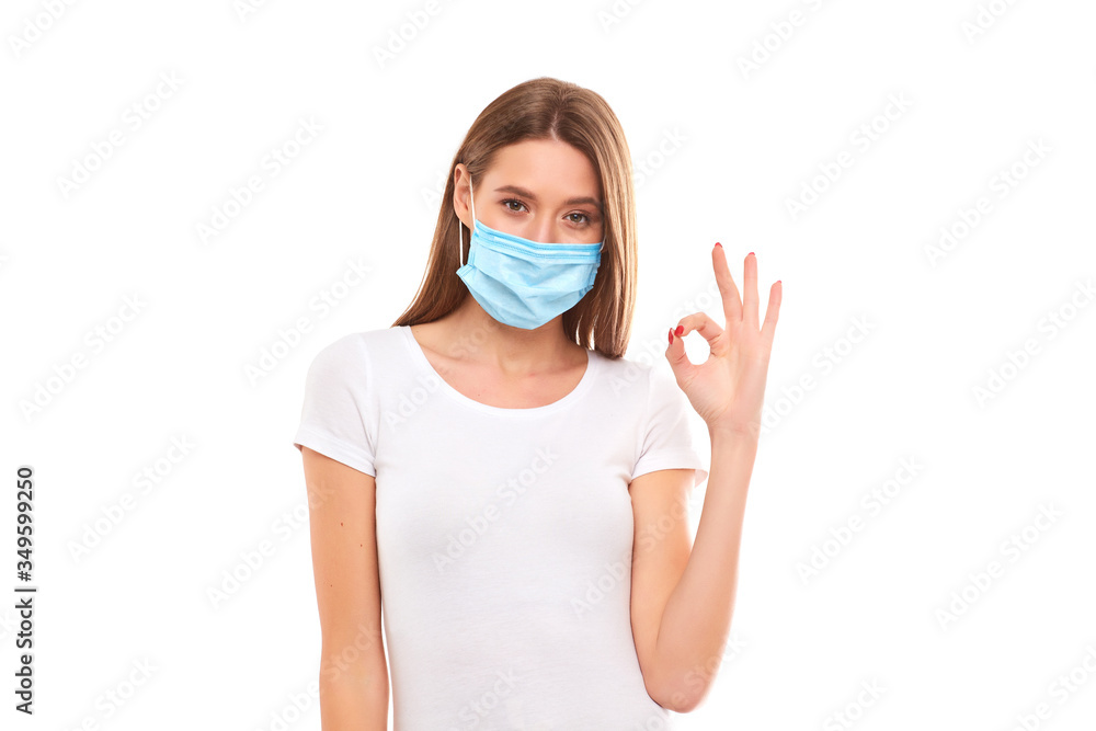 European girl in a medical mask, shows ok. Conceptual photo on the theme of the Covid 2019 pandemic.
