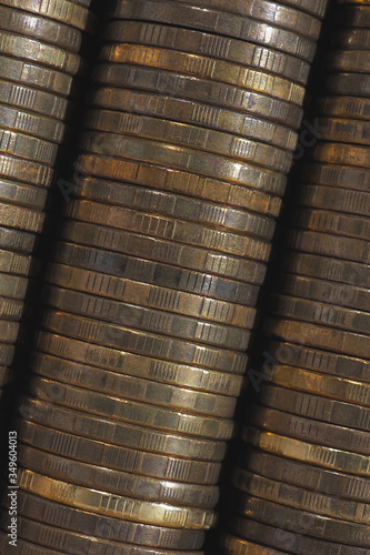 Background from stacks and edges of yellow brass coins placed at an angle diagonally across the image. 10 Russian rubles close up. Dark vertical backdrop or wallpaper on economic, banking topic. Macro