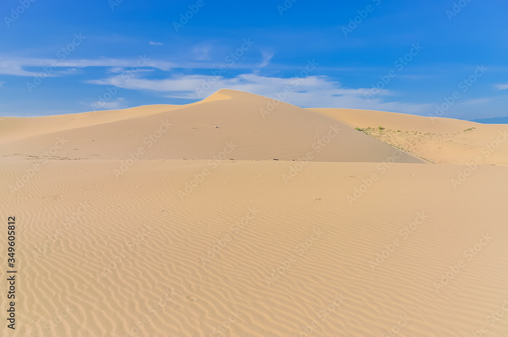 Many ripples wave lead to peak of sand dunes under sunny blue cloud sky in Nam Cuong, Phan Rang, Viet Nam.