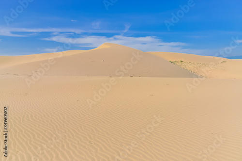 Many ripples wave lead to peak of sand dunes under sunny blue cloud sky in Nam Cuong  Phan Rang  Viet Nam.