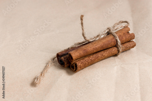 Cinnamon sticks tied with jute rope on beige paper. Food concept