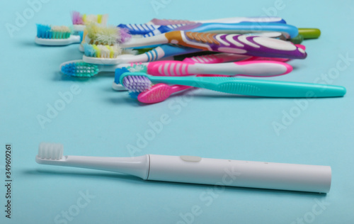 New Electric toothbrush and old used toothbrushes on a blue background close-up. Oral Care