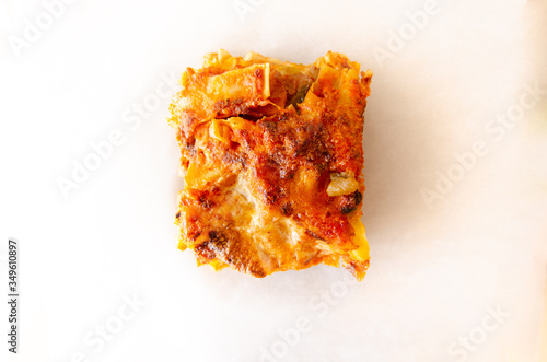 Hand made close up vegetable lasagna on baking cooking paper isolate on white top view