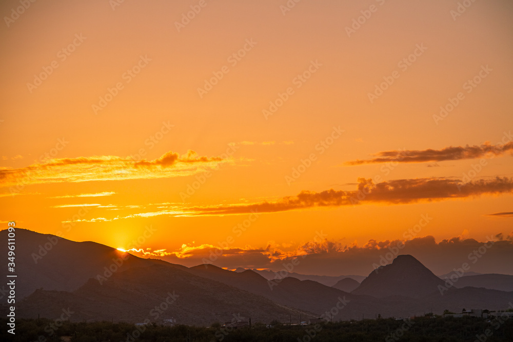 Naklejka premium The sun setting behind mountainsThe sun setting behind mountains in the Sonoran Desert of Arizona. in the Sonoran Desert