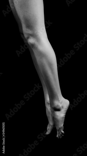 black and white photo of female legs standing on fingertips isolated on black background
