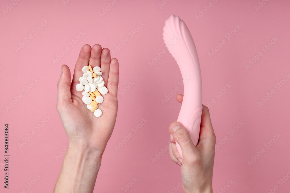 Hands holding sex toy and pills on pink background. Sex stimulants. Hands holding sex toy and pills on pink background. Sex stimulants.