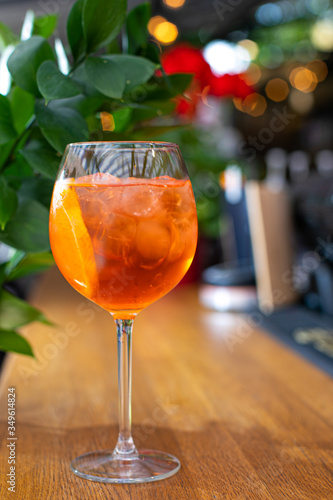Aperol is an alcoholic cocktail. Orange. Cold drink with ice cubes. The glass is on the bar. Green in the background. The background is blurred. Menu for restaurants, cafes and bars.