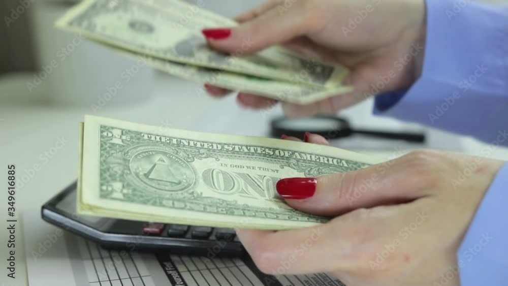 Woman counts cash on a backround of a desk with a calculator, coins, magnifier Woman counts cash on a backround of a desk with a calculator, coins, magnifier