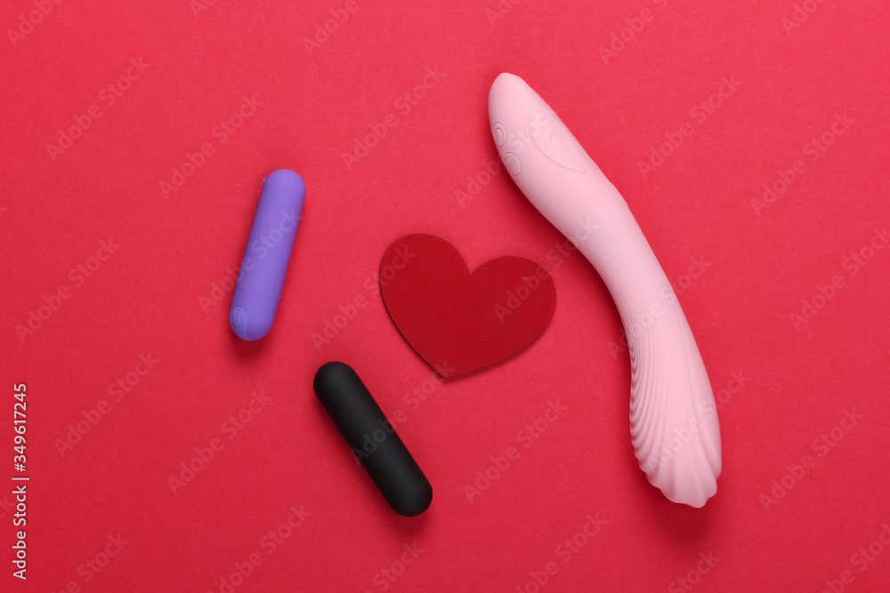 Sex concept. Sex toys and red heart on red background. Top view Sex concept. Sex toys and red heart on red background. Top view