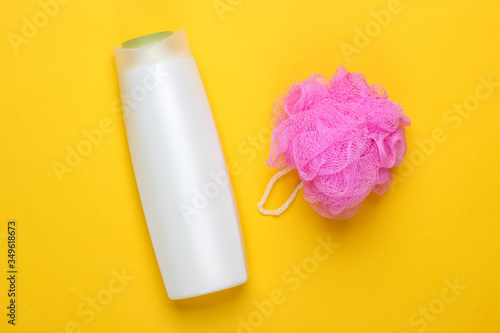 Bath, beauty products on yellow background. Shampoo bottle and sponge. Top view. Flat lay