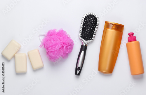 Bath, beauty products on white background. Shampoo bottle, sponge, soap and hair brush. Top view. Flat lay
