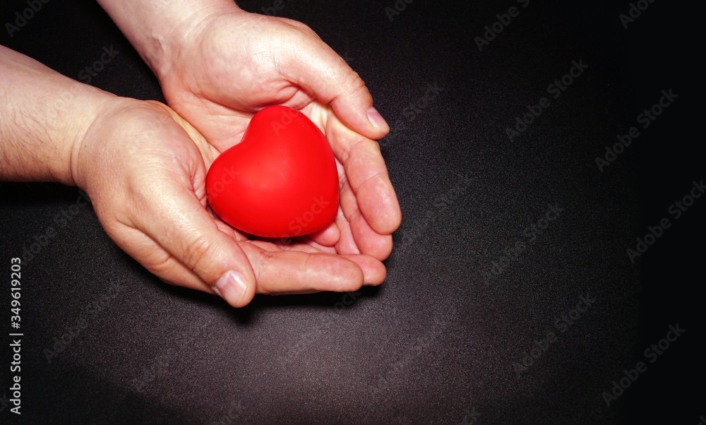 Man hands with red plastic heart.