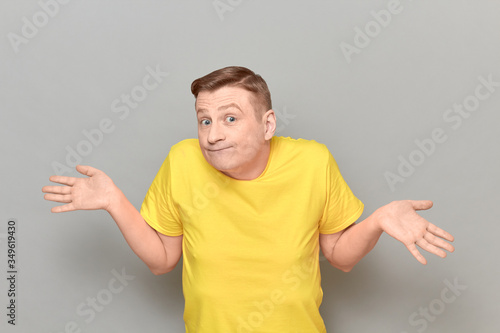 Portrait of funny puzzled man shrugging shoulders and spreading hands