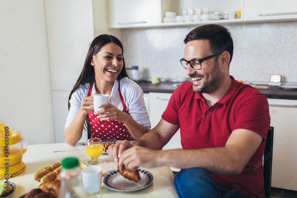 Cheerful young couple having breakfast in kitchen at home. Cheerful young couple having breakfast in kitchen at home.