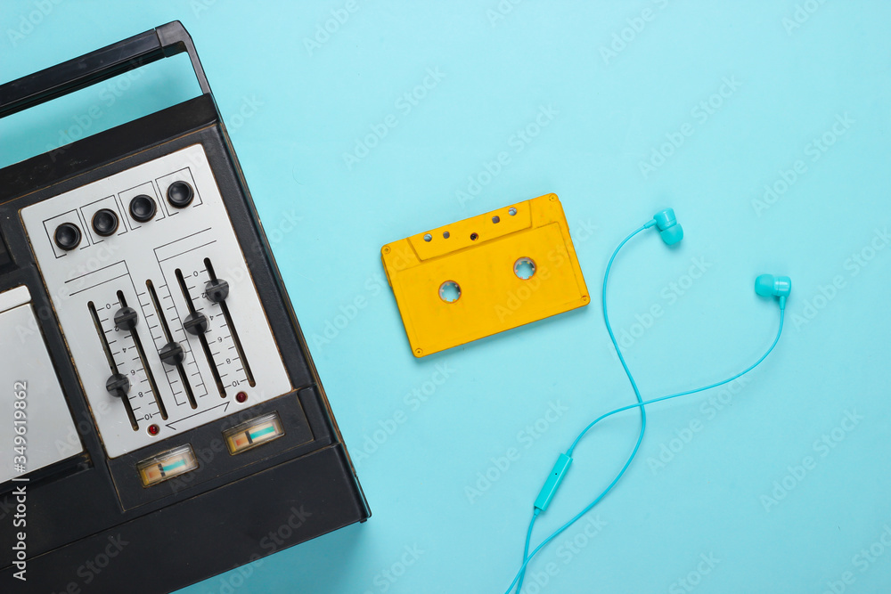Fototapeta premium Retro audio tape recorder, earphones and audio cassette. Retro media on blue background. Top view. 80s