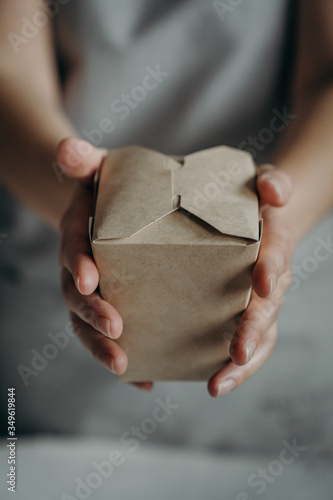 Close up female hold in hand brown clear empty craft paper box for give takeaway. Packaging template mock up. Delivery service concept. Copy space. Advertising area