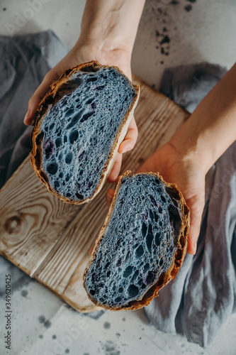 Woman hands Holding  fresh organic artisan bread blue color. Healthy eating, buy local, homemade bread recipes concept. Top view, flat lay