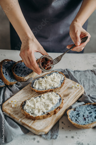 Woman spreading ricotta cheese and onion marmalade onto slice of bread, mid section