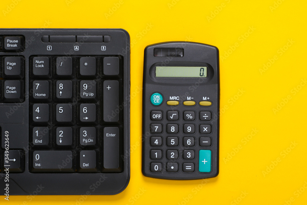 Pc keyboard and calculator on yellow background. Working space. Top view Pc keyboard and calculator on yellow background. Working space. Top view