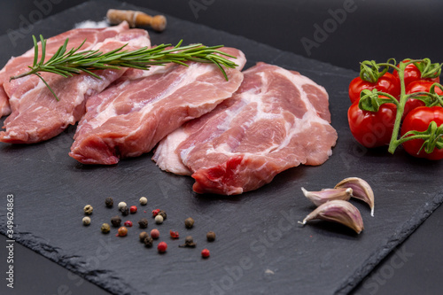 pork raw steak and ingredients on black slate