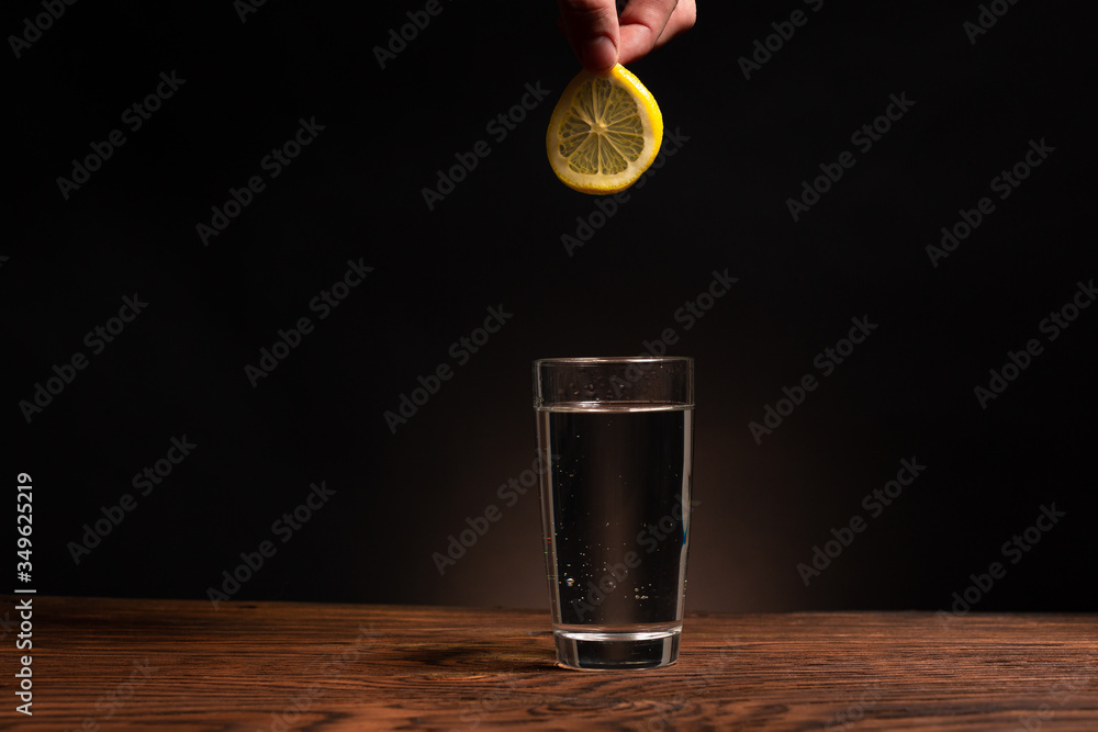 lemon in glass of water on black background