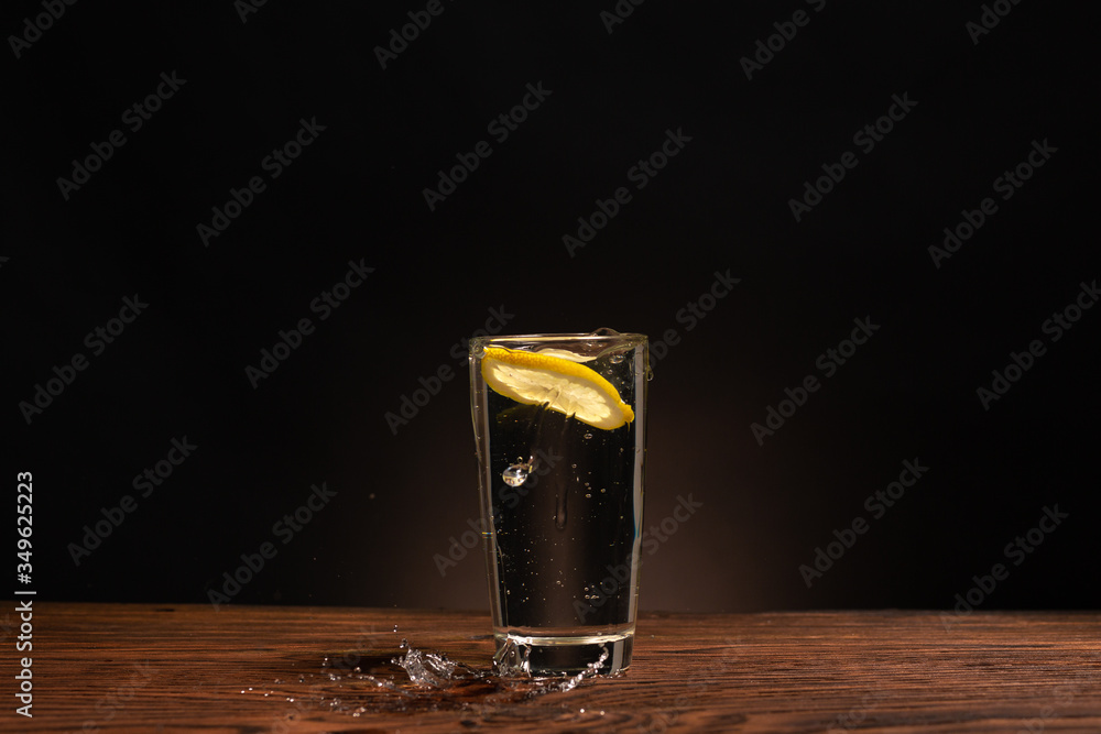 lemon in glass of water on black background