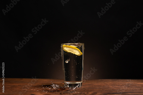 Obraz na płótnie lemon in glass of water on black background w salonie