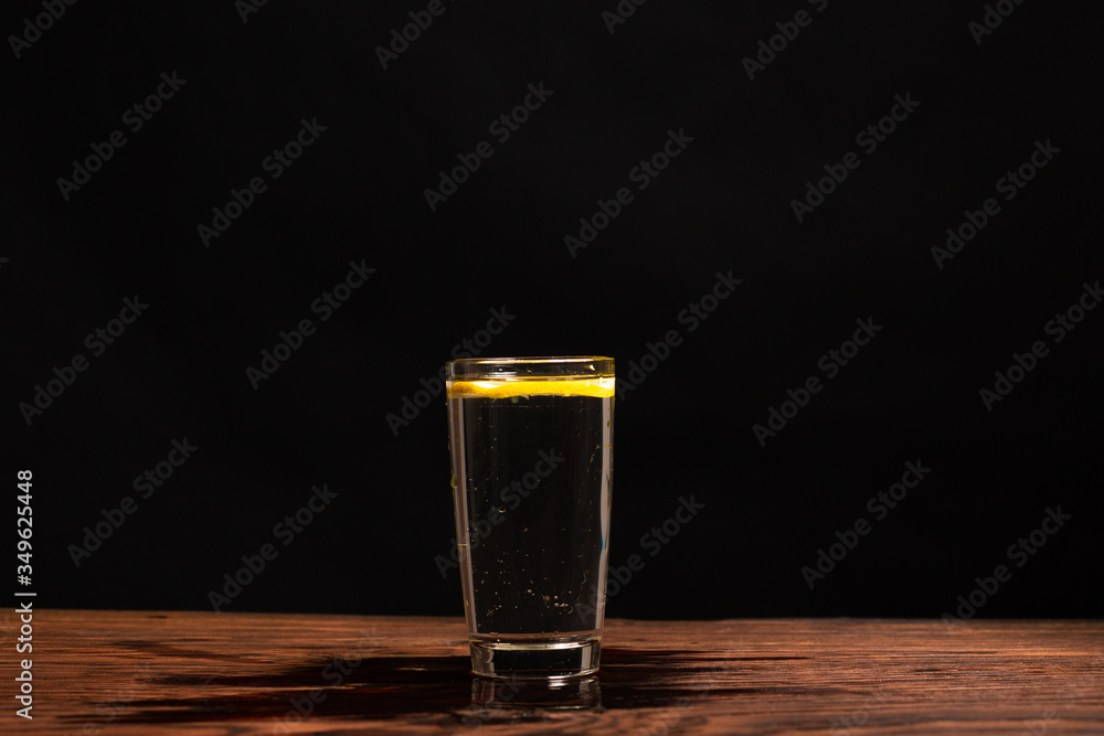 lemon in glass of water on black background