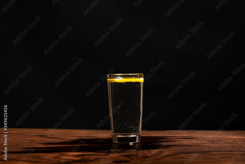 lemon in glass of water on black background