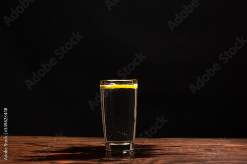 Obraz na płótnie lemon in glass of water on black background w salonie