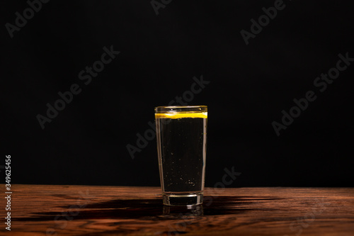 Obraz na płótnie lemon in glass of water on black background w salonie