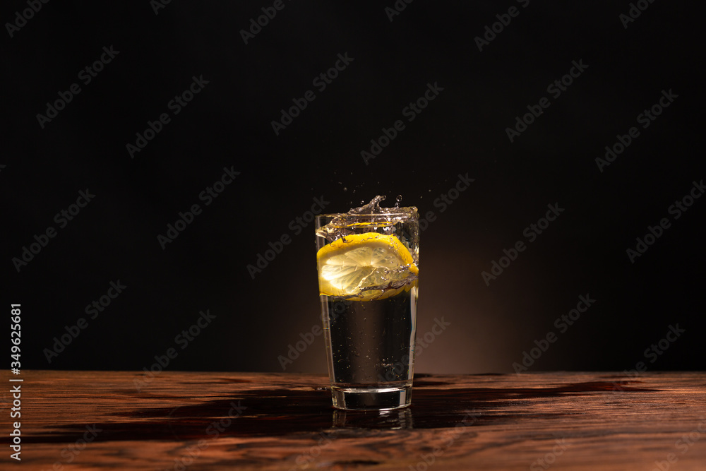 lemon in glass of water on black background