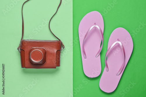 Flip flops and retro camera on green paper background. Trip, vacation concept. Summer fashion, holiday. Beach accessories.