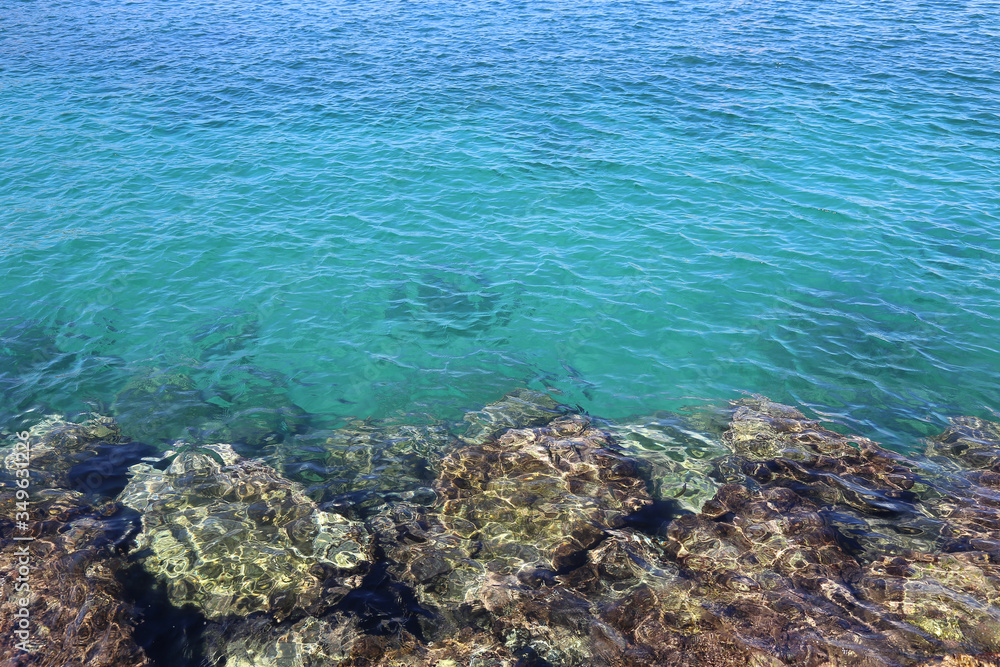 Bright turquoise sea water and stones near the shore Bright turquoise sea water and stones near the shore