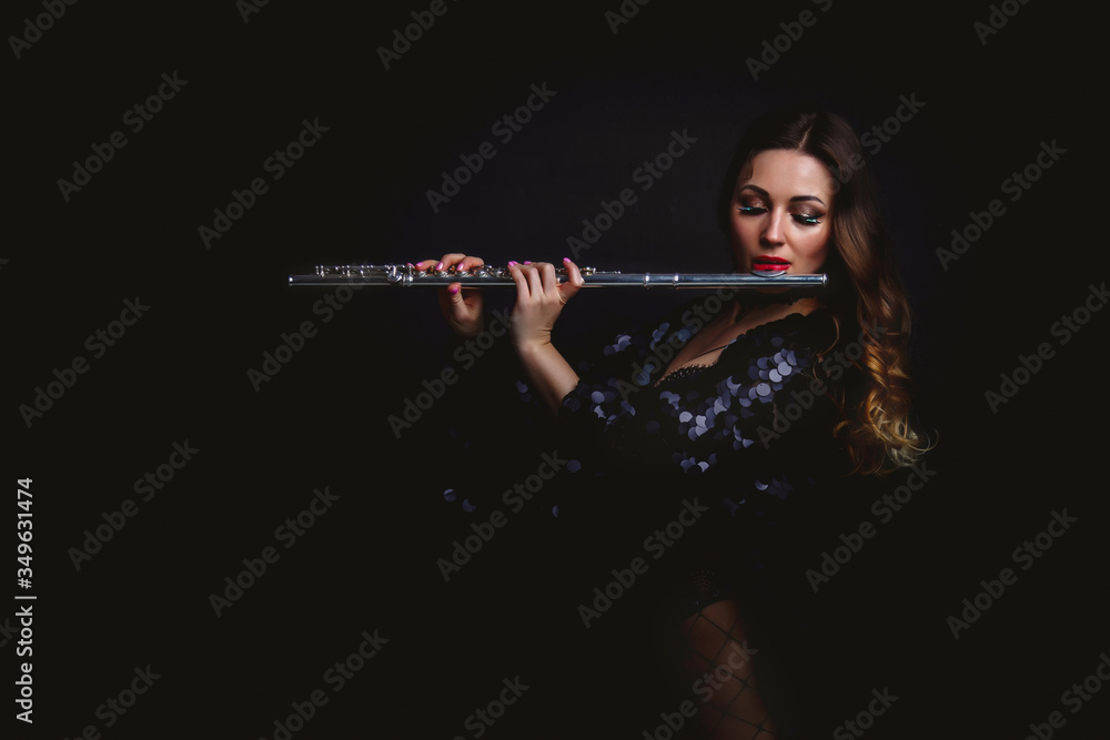 Female girl artist in suit with flute on black background. Flute in hand. Player with orchestra instrument. Isolated on black. The concept of music poster