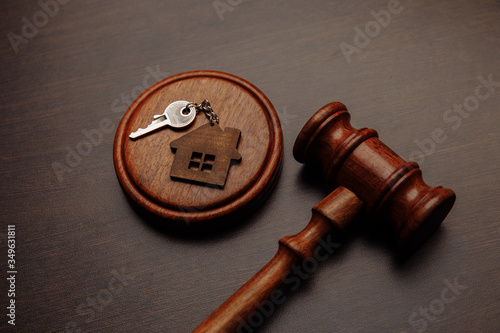 Judge gavel and key chain in shape of two splitted part of house on wooden background. Concept of real estate auction or dividing house when divorce, division of property, real estate, law system. photo