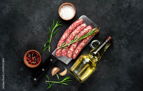  raw sausages with ingredients over a meat knife on a stone background with copy space for your text