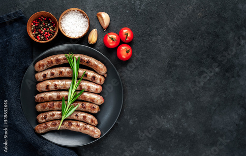 
grilled sausages with ingredients on a plate on a stone background with copy space for your text