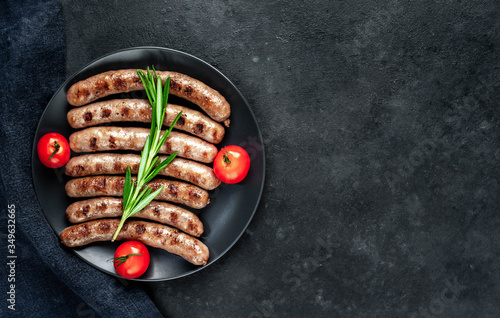 
grilled sausages with ingredients on a plate on a stone background with copy space for your text