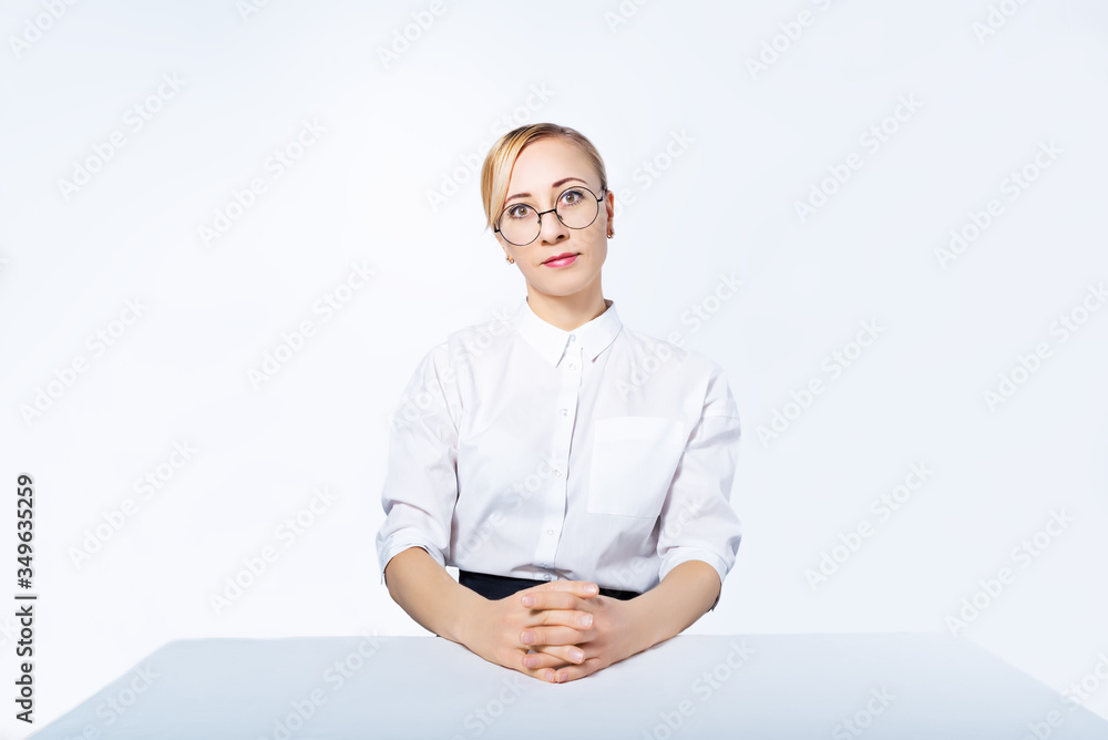 Blonde business woman in a suit is sitting at a table on a white background Blonde business woman in a suit is sitting at a table on a white background