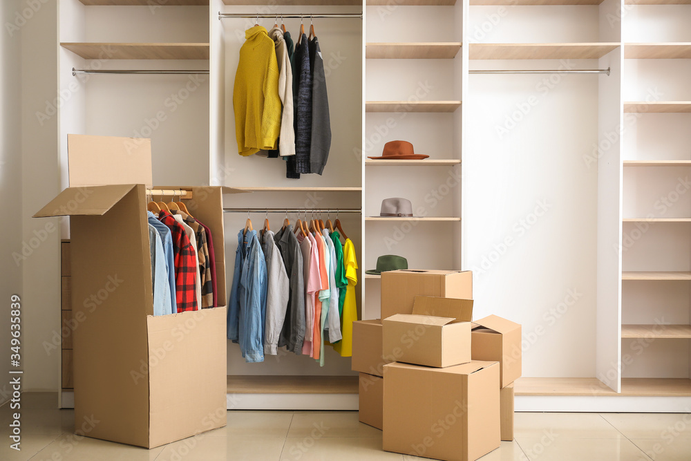 Moving boxes near wardrobe in dressing room Photos | Adobe Stock