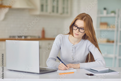 Online education. Girl in glasses studying using a laptop video call chat web camera watching college university at home.