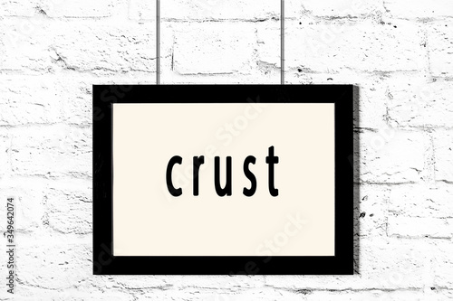 Картината върху платно Black frame hanging on white brick wall with inscription crust