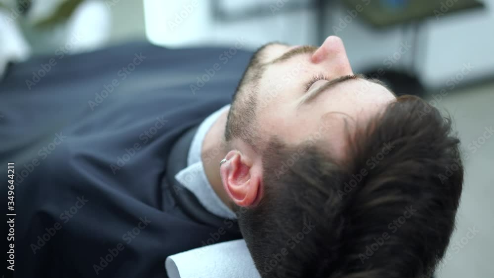 Young adult beautiful caucasian woman hairdresser cuts beard handsome man at modern barbershop Happy guy sitting chair men beauty salon. beard care. metrosexual. Female barber in black gloves serving Young adult beautiful caucasian woman hairdresser cuts beard handsome man at modern barbershop Happy guy sitting chair men beauty salon. beard care. metrosexual. Female barber in black gloves serving
