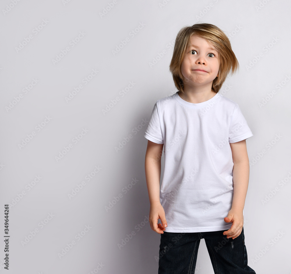 Little blond bro in black and white casual wear. He is smiling, posing on a white background. Childhood, fashion, advertising. Little blond bro in black and white casual wear. He is smiling, posing on a white background. Childhood, fashion, advertising.