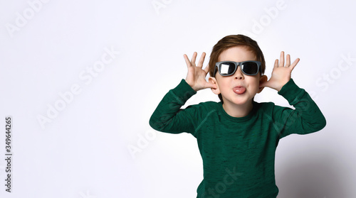 male in sunglasses and green jumper. He is fooling around and showing his tongue, posing isolated on white