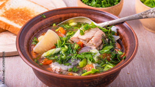 Simple fish soup with salmon and vegetables in a clay bowl