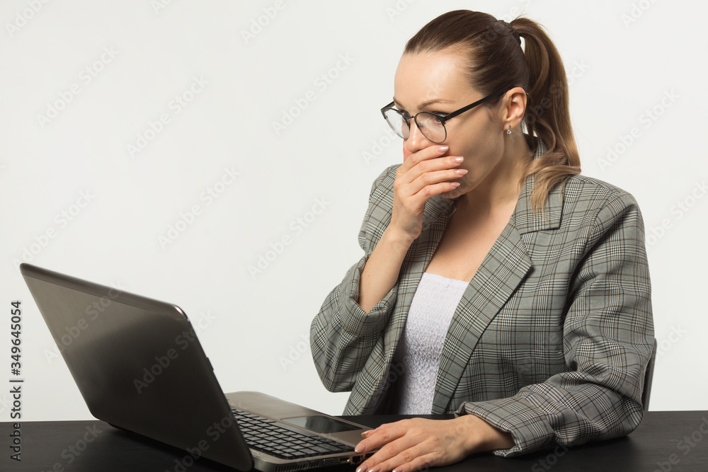 beautiful young woman at a table with a laptop on a white background beautiful young woman at a table with a laptop on a white background