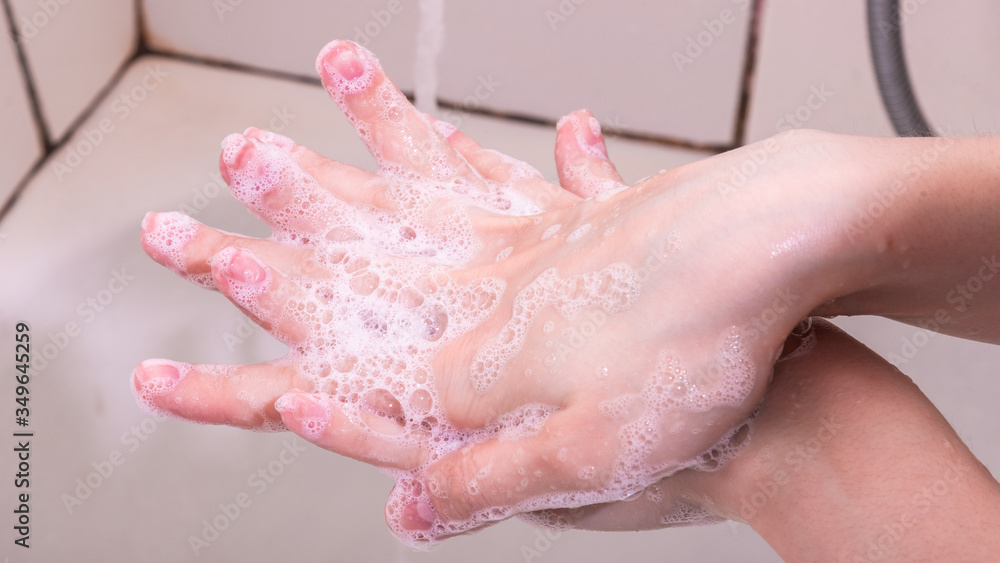 Fototapeta premium Woman washes hands with liquid soap, soap suds, close-up